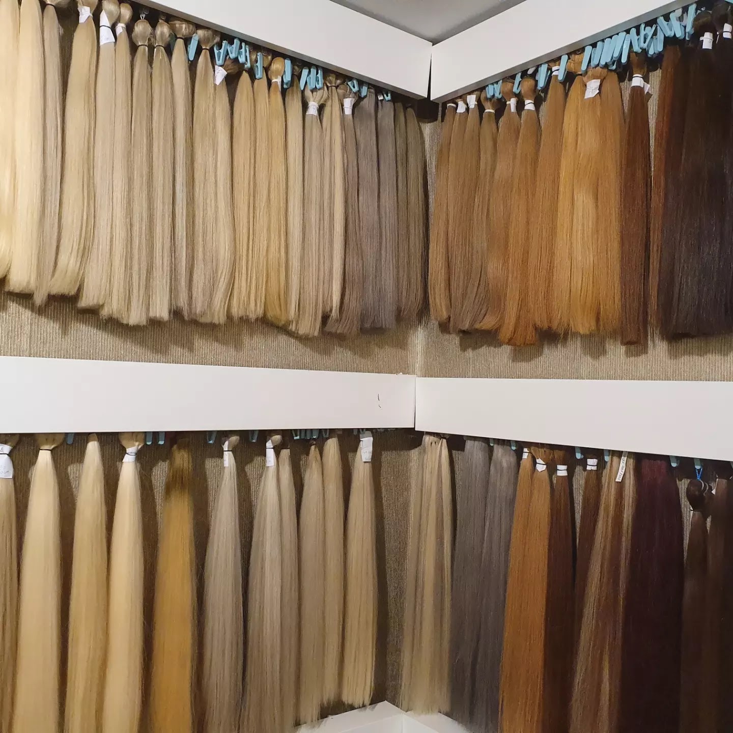 De haarwand in de salon: rijen bundels van licht blond via karamel tot donkerbruin