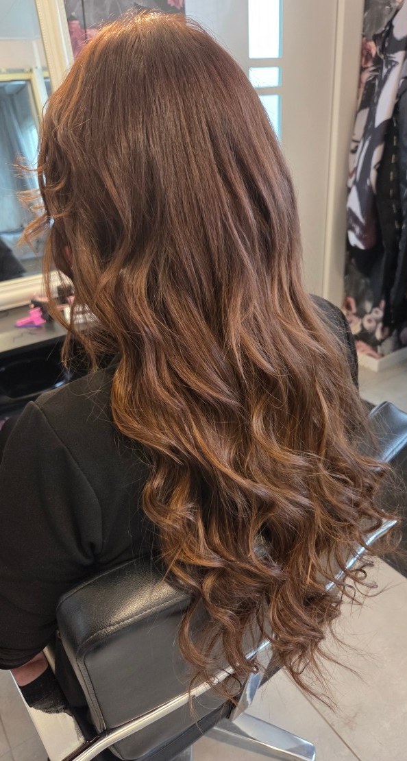 Lang bruin haar met krullen in de salonstoel